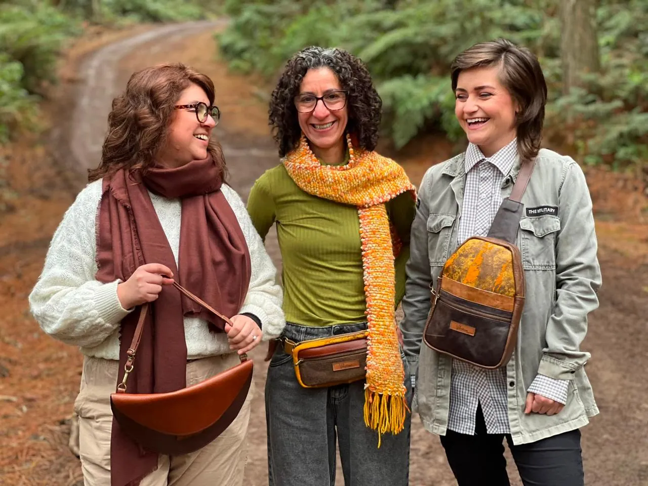 Três mulheres numa trilha usando pochetes e cachecóis